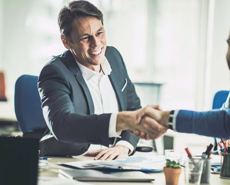 Image of 2 business men shaking hands in a meeting room